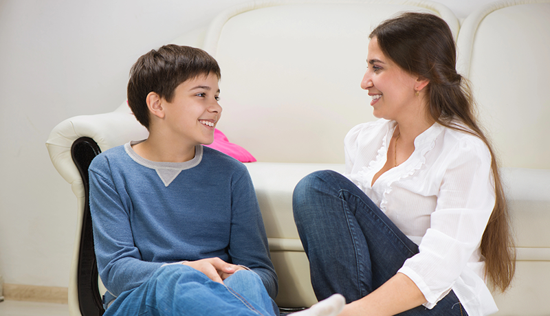 tween boy talking to mom on living room floor